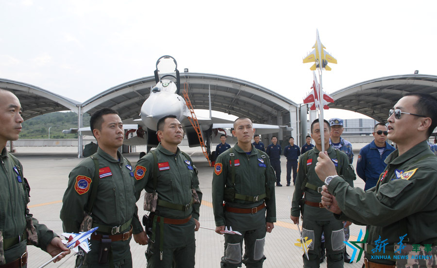 ↑艦載航空兵某部司令員戴明盟向飛行員演示空中飛行注意事項。